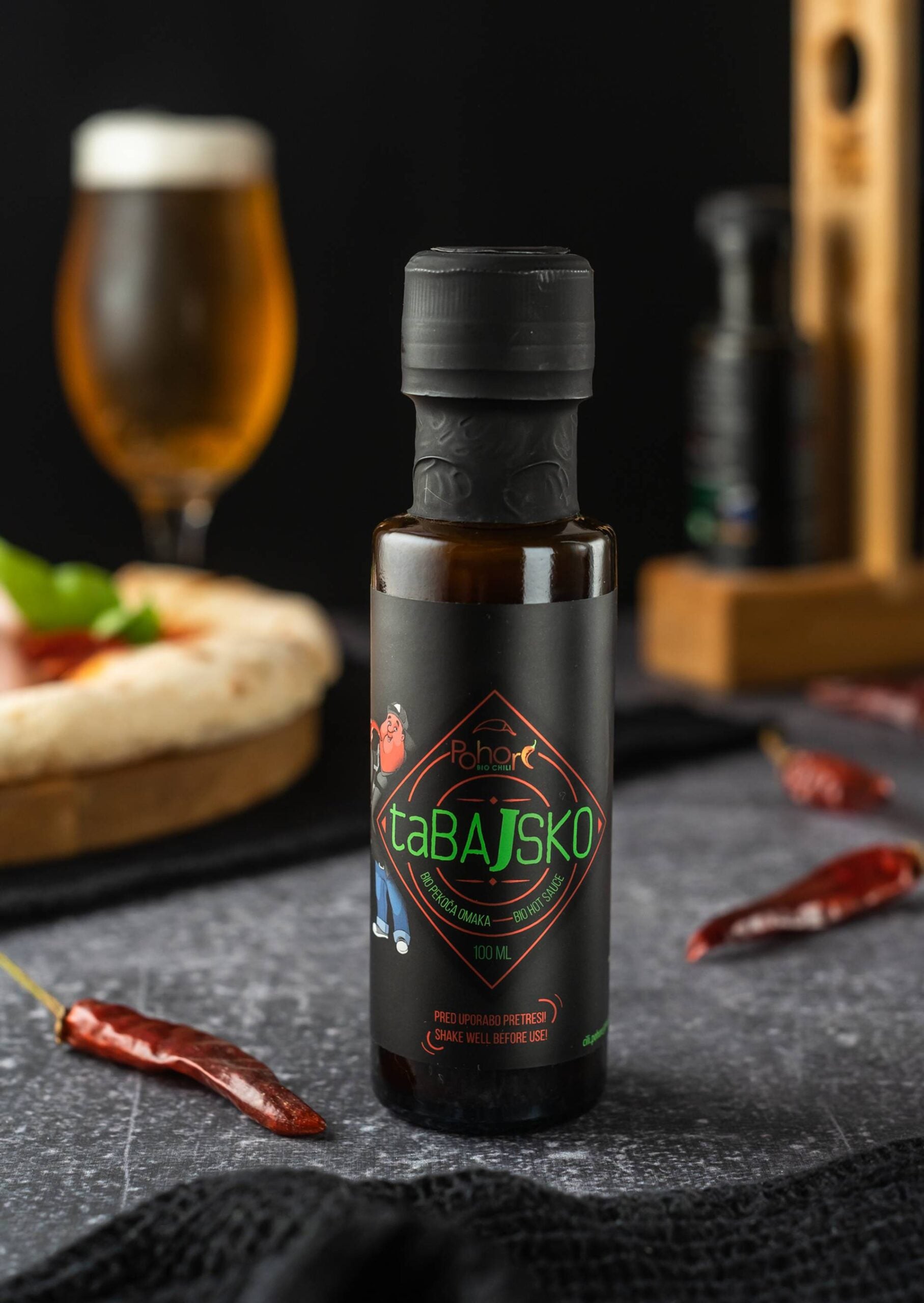 Čili omaka Pohorc taBAJSKO s svežimi čiliji in hrastovimi sodčki. Rahlo pikantna fermentirana omaka iz slovenskih ekoloških sestavin.